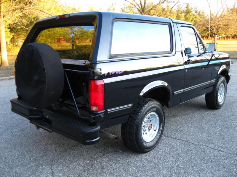 Black Ford Bronco with spare tire on rear door, chrome trim, and side stripe