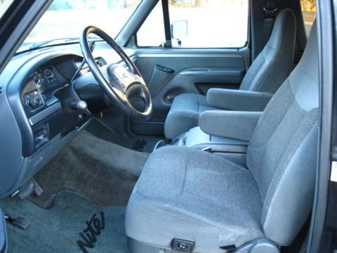 1994 Ford Bronco - The interior of a truck features cloth bucket seats and floor mats with 'Nite' lettering visible.
