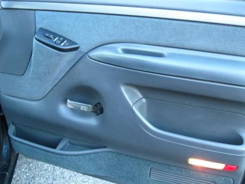 1994 Ford Bronco - Interior door panel of a 1994 Ford Bronco, showing window controls and a pull handle.