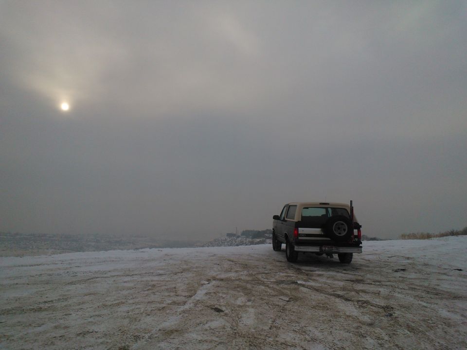 1992 Ford Bronco parked on a snowy landscape under a hazy sun