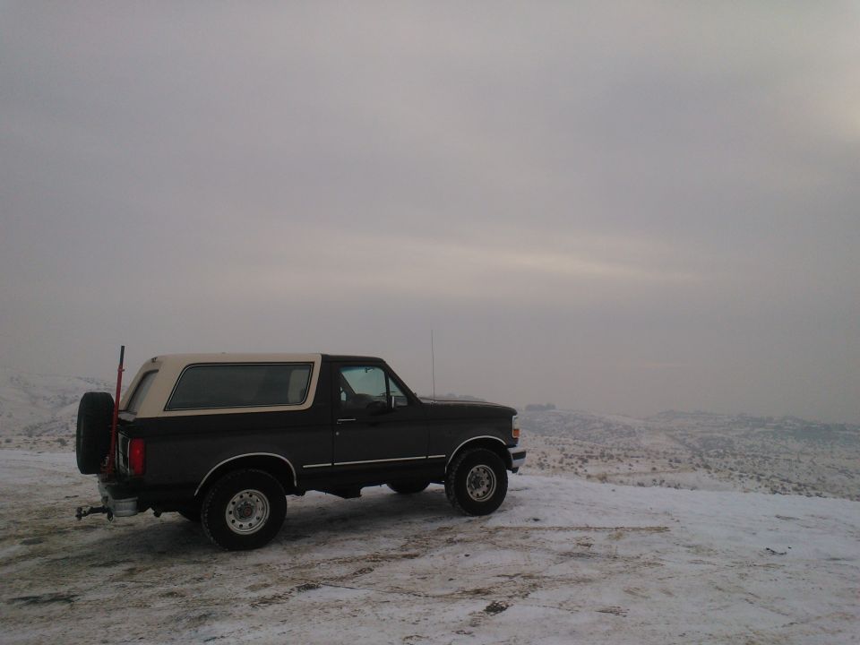 1992 Ford Bronco parked on a snowy hillside, rear quarter view.
