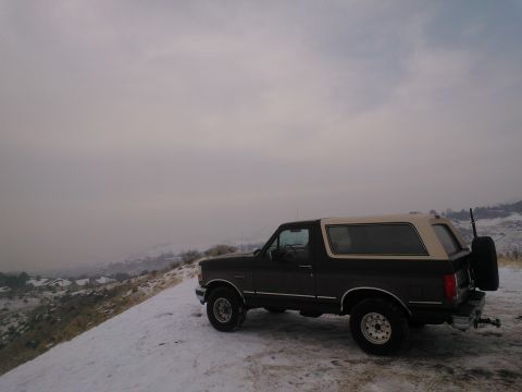1992 Ford Bronco - A 1992 Ford Bronco sits on a snow-covered ridge overlooking a valley.
