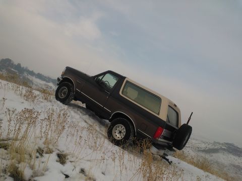 1992 Ford Bronco - Ford Bronco navigates a snowy hillside, showing its rear-mounted spare tire.