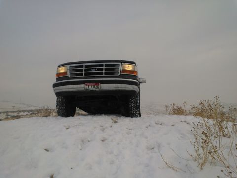 1992 Ford Bronco - A 1992 Ford Bronco sits on a snowy hill, its front grille clearly visible against the overcast sky.