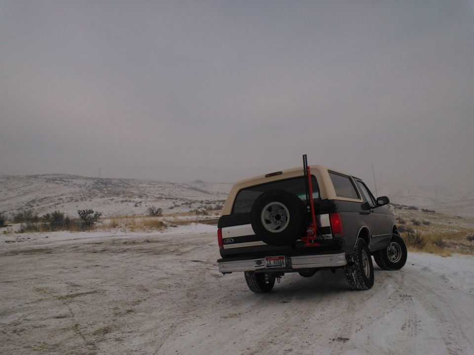 1992 Ford Bronco on a snowy road, spare tire mounted on the back, jack visible