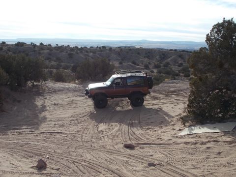 1986 Ford Bronco II - 1986 Ford Bronco II navigating a sandy off-road trail in a desert environment.