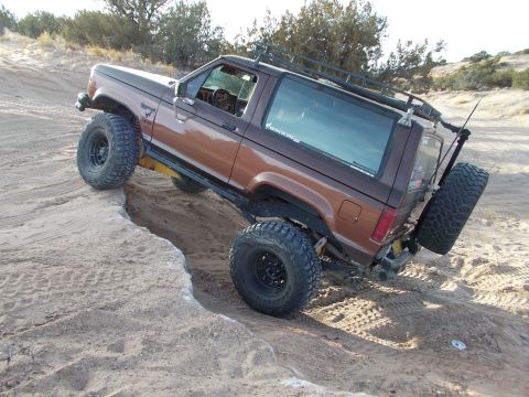 1986 Ford Bronco II - This 1986 Ford Bronco II is navigating a steep dirt incline, demonstrating its off-road capabilities.