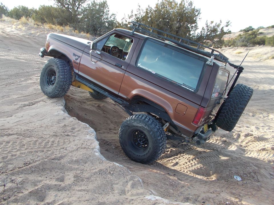1986 Ford Bronco II with large tires climbing a dirt embankment