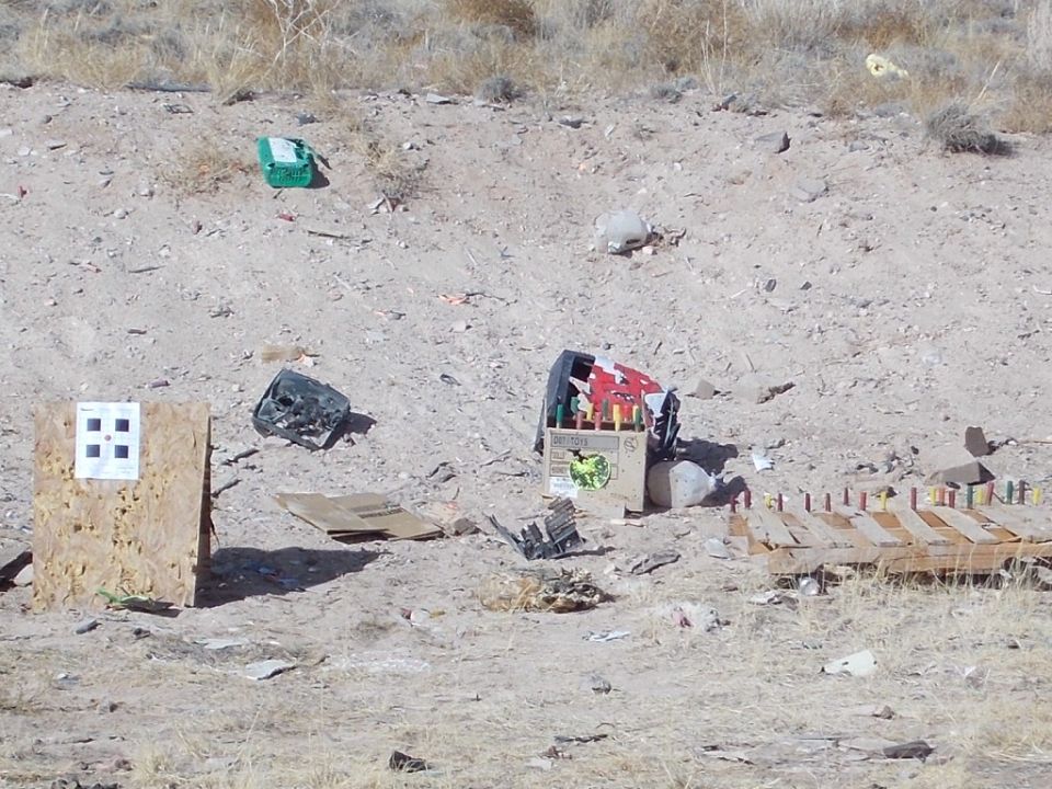 target and debris scattered on dry ground, with a wooden pallet in the foreground