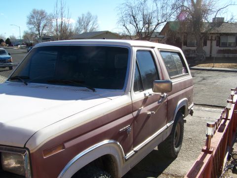 1981 Ford Bronco - A two-tone brown and white Ford Bronco is parked on a street, viewed from the front quarter angle.
