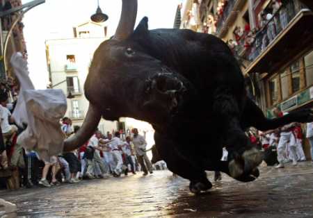1988 Ford Bronco - A bull charges down a street during a festival, with onlookers in buildings and on the ground.