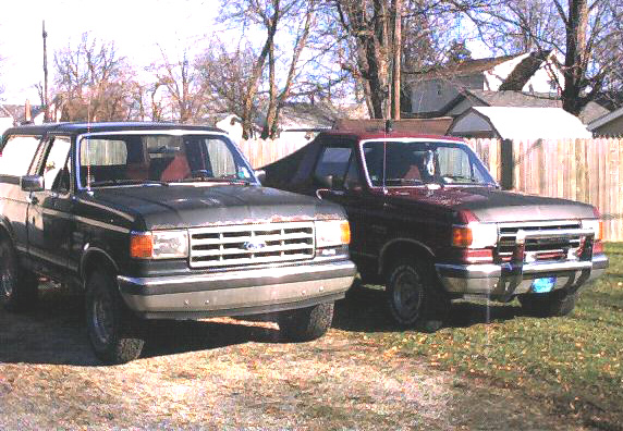 Two dark Ford Broncos parked side-by-side, front 3/4 view