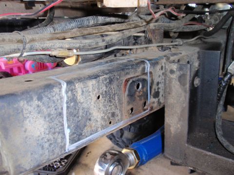 1971 Ford Bronco - Detail of vehicle frame showing markings for modification, with suspension parts in view.