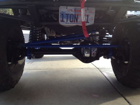 1971 Ford Bronco - The underside of a heavily modified vehicle reveals custom suspension parts and large off-road tires.