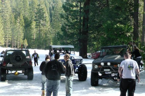 1971 Ford Bronco - Several off-road vehicles, including a 1971 Ford Bronco, are parked in a snowy forest setting.