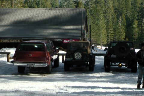 1971 Ford Bronco - Three SUVs are parked in the snow outside a building labeled Toms Cabin.