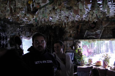 1971 Ford Bronco - A room's interior is heavily decorated with US currency, with two individuals present and a view of the outdoors through a window.