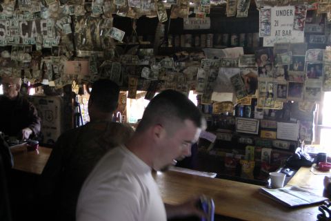 1971 Ford Bronco - The interior of a bar is decorated with numerous dollar bills and photographs adorning the walls, with a sign stating "Under 21 At Bar".