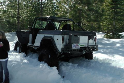 1971 Ford Bronco - A 1971 Ford Bronco navigates through deep snow, its rear visible with a license plate indicating the year.