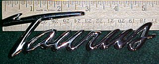 2003 Ford Expedition - A chrome emblem reads 'Taurus' and is placed next to a ruler for scale.