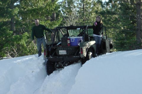 1971 Ford Bronco - A Ford Bronco navigates through deep snow with two people observing.