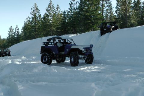 1971 Ford Bronco - Multiple off-road vehicles navigate a snowy terrain, with one prominently featured in the foreground.