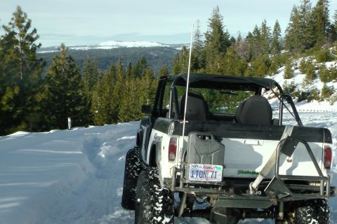1971 Ford Bronco - This SUV is equipped for off-road adventures in snowy conditions, with a prominent gas can and spare tire carrier.