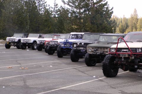 1971 Ford Bronco - Several off-road SUVs, including multiple first-generation Ford Broncos, are lined up in a parking lot.