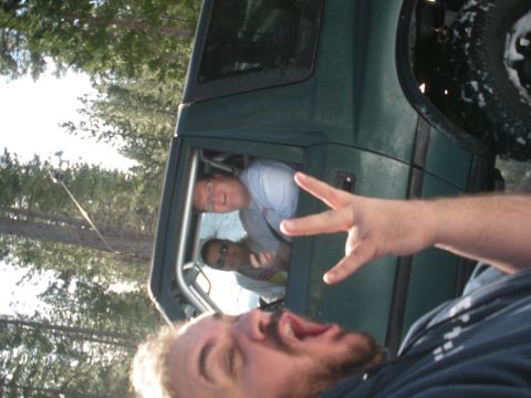 1971 Ford Bronco - People pose for a selfie inside a green SUV, with trees and sky visible in the background.