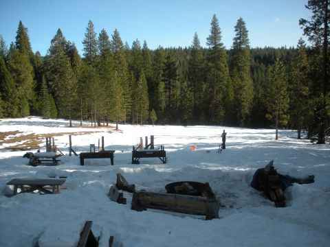 1971 Ford Bronco - A winter scene with snow-covered ground, picnic tables, and a dense forest in the background.