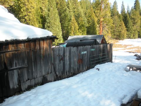 1971 Ford Bronco - A turquoise truck is seen behind a rustic wooden fence in a snowy landscape, with trees in the background.