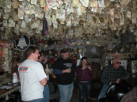1971 Ford Bronco - A bar interior is covered in hanging currency, with several people gathered.