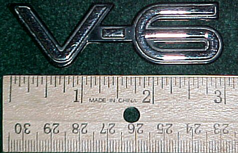 2003 Ford Expedition - A V6 emblem is shown next to a ruler for scale. Text on the ruler indicates it was made in China.