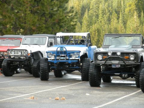 1971 Ford Bronco - Several modified off-road SUVs, including a 1971 Ford Bronco, are parked together outdoors.
