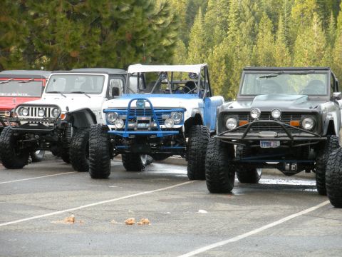 1971 Ford Bronco - A lineup of , modified SUVs, their off-road capabilities with large tires and custom bumpers.