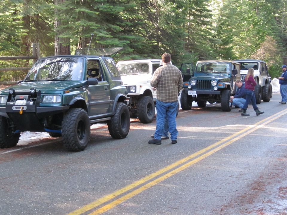 Green off-road SUV with winch and large tires parked on a road