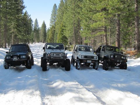 1971 Ford Bronco - Multiple off-road vehicles are parked on a snowy forest road.