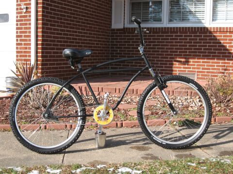 1994 Ford Bronco - A custom black bicycle with knobby tires and a yellow chainring is shown from the side in front of a brick house.