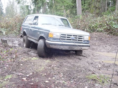 1987 Ford Bronco - Ford Bronco navigating a challenging muddy off-road course.