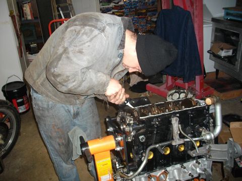 1989 Ford Probe - A person works on an engine block mounted on a stand in a garage setting.