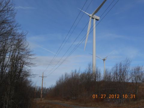 1986 Ford Bronco - Two wind turbines stand tall against a clear blue sky, with power lines stretching across the frame.