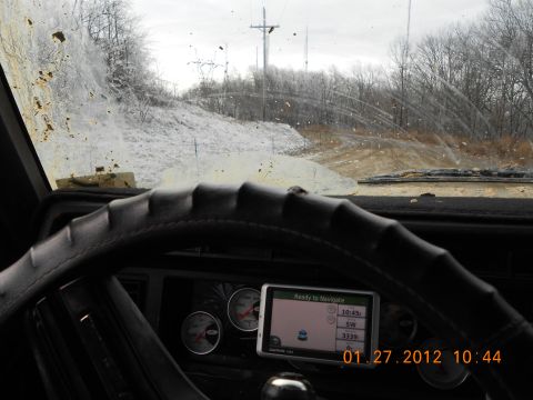 1986 Ford Bronco - View from inside a vehicle with a dirty windshield, showing the dashboard and a GPS unit on a snowy day.