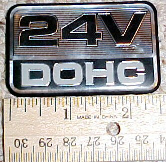 2003 Ford Expedition - A close-up view of a '24V DOHC' emblem, with a ruler indicating its size.