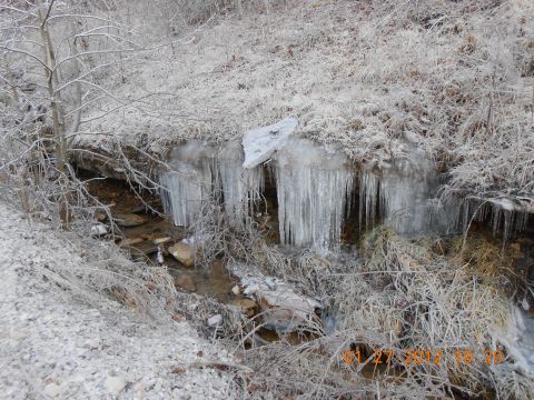 1986 Ford Bronco - A winter scene shows a small stream partially frozen with icicles forming along the bank.