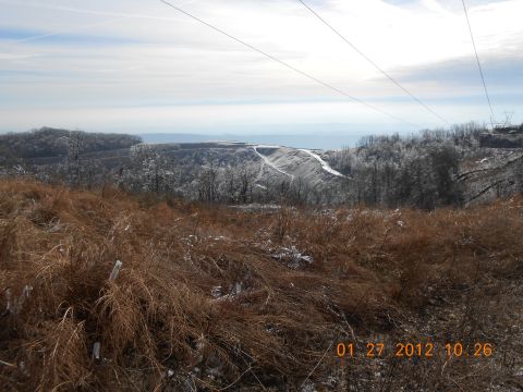 1986 Ford Bronco - A wide view of a winter landscape dry grass in the foreground and a distant industrial area under a cloudy sky.