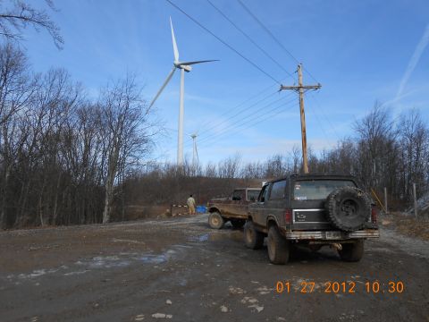 1986 Ford Bronco - A black 1986 Ford Bronco is parked on a dirt road near wind turbines, with another vehicle behind it.