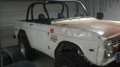 1970 Ford Bronco - A white 1970 Ford Bronco with a roll cage and racing decals is parked indoors.