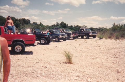 1989 Ford Bronco - A group of off-road vehicles are gathered in a desolate, rocky area.