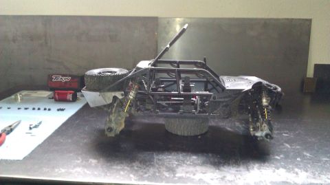 1996 Ford Bronco - An RC rock crawler sits on a workbench, surrounded by tools and spare parts, ready for modification or repair.