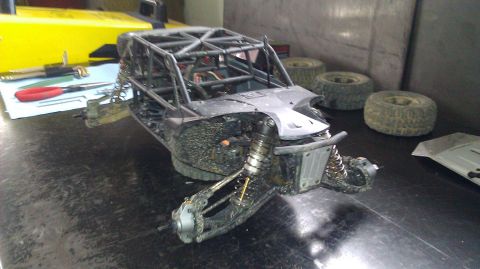 1996 Ford Bronco - A damaged remote control buggy sits on a workbench with spare tires nearby.